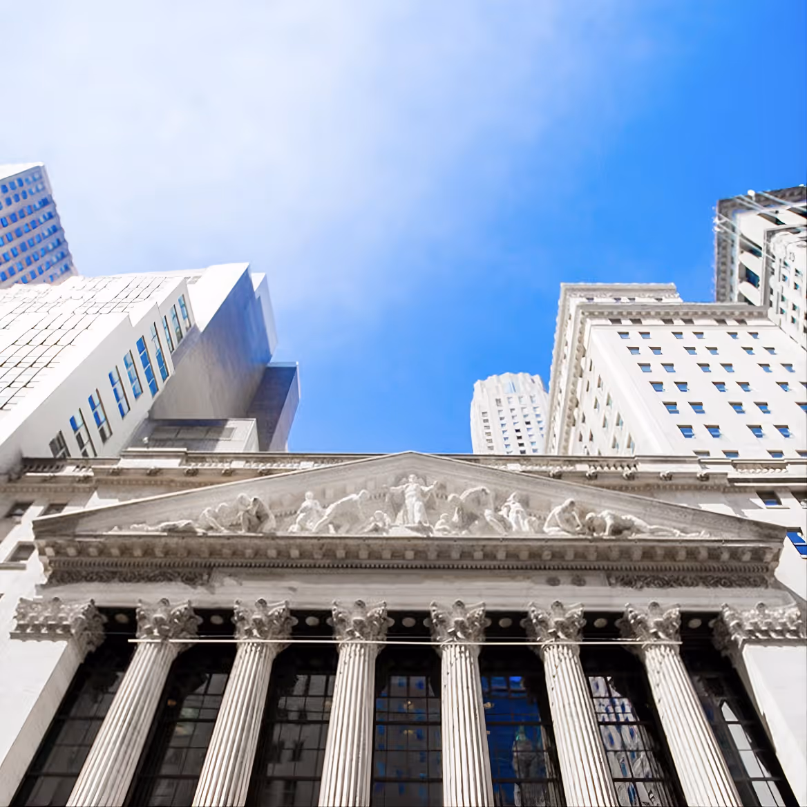 Low angle view of a classical building facade with columns under a clear blue sky.