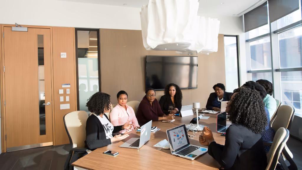 A diverse team of professionals collaborates around a conference table with laptops, representing the organizational leaders who need proctoring solutions that work at scale without adding administrative burden.
