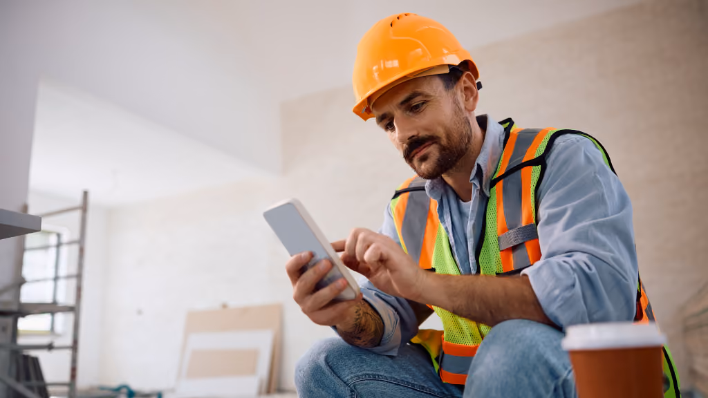 Construction worker onsite looking at his phone while taking an workplace safety online assessment
