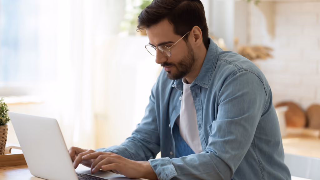 A young man types on his laptop