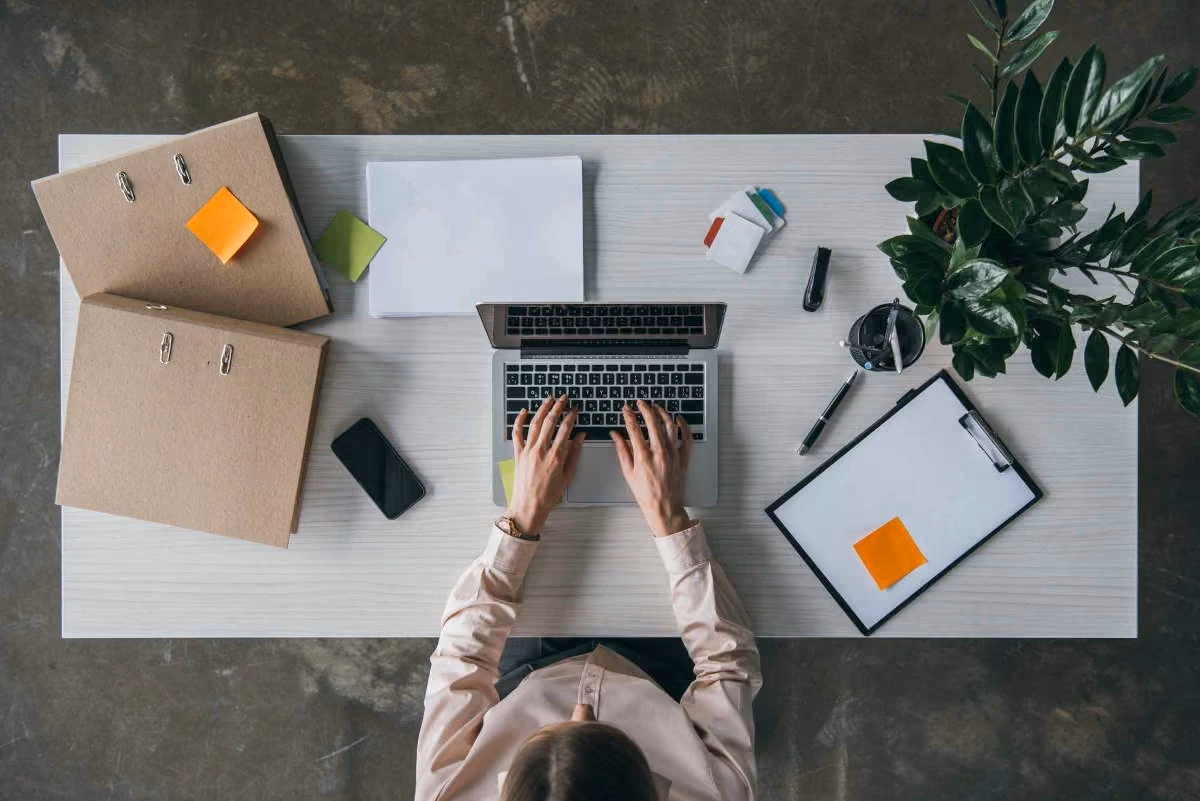 A professional works at a laptop from above, representing the browser-based online proctoring experience that requires no software installation.