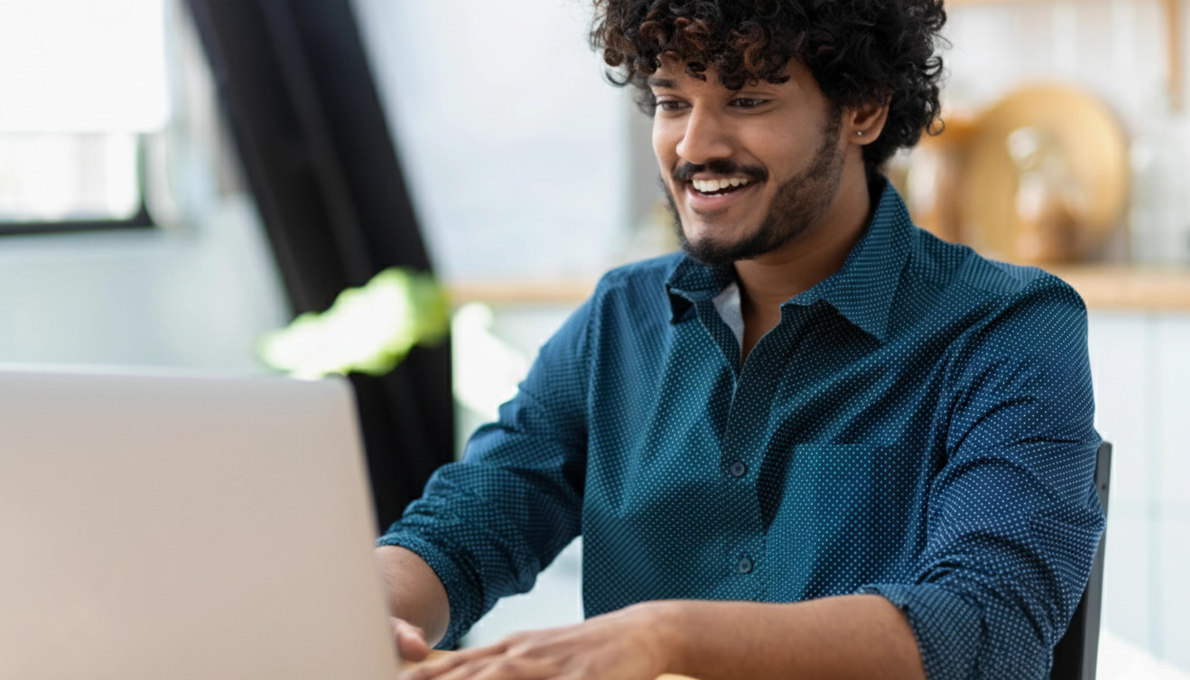 A smiling student takes an online exam on a laptop in a bright home setting, representing a calm, privacy-first remote proctoring experience.