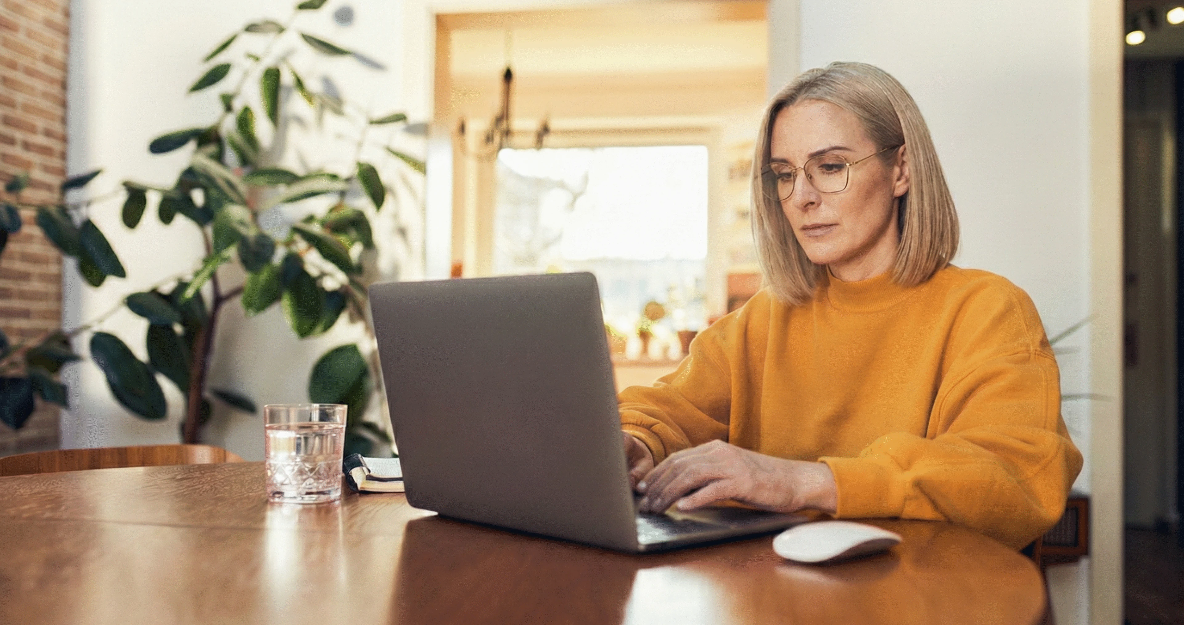 Woman working on laptop at home representing online exam proctoring and academic integrity in an AI-enabled learning environment.