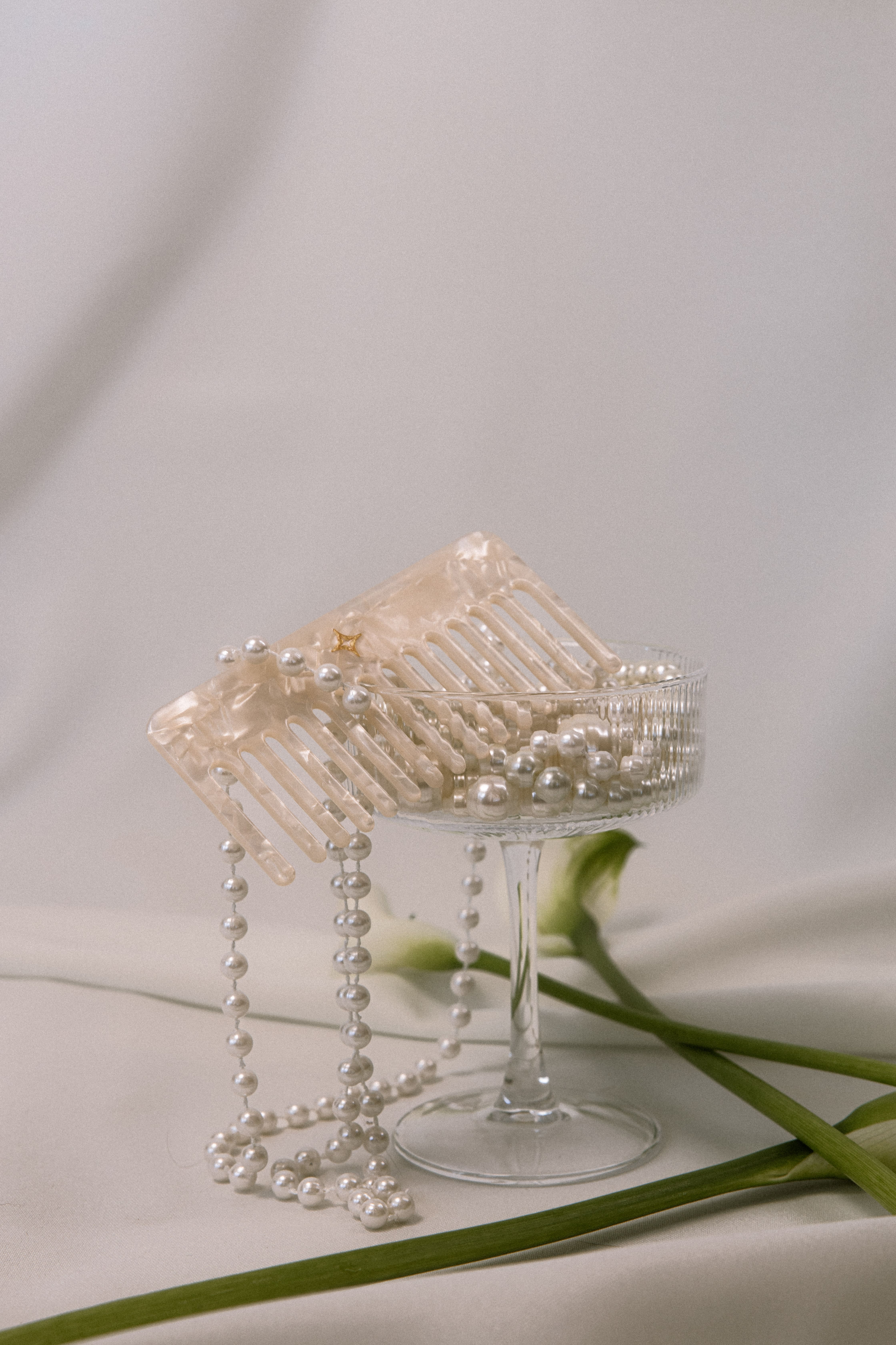 Young man with curly dark hair and light beard smiling, wearing a white shirt and dark jacket against a gray background.
