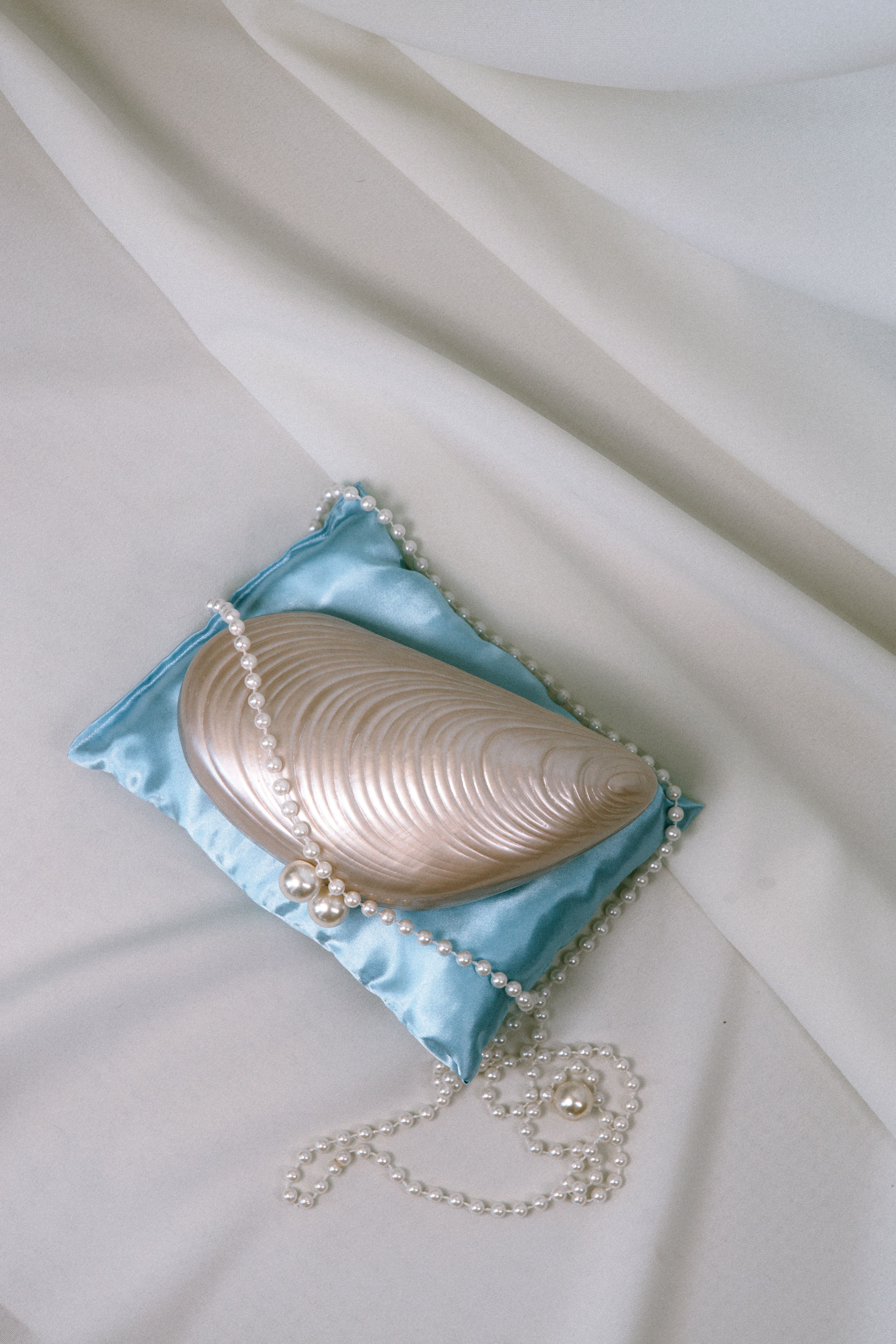 Hand holding a frosted glass bottle with a black cap surrounded by splashing water against a gradient background.