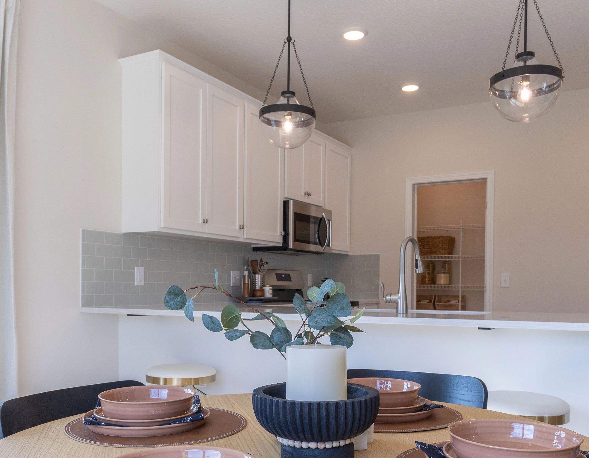Modern kitchen with white cabinets, stainless steel appliances, and a dining table set with brown dishes.