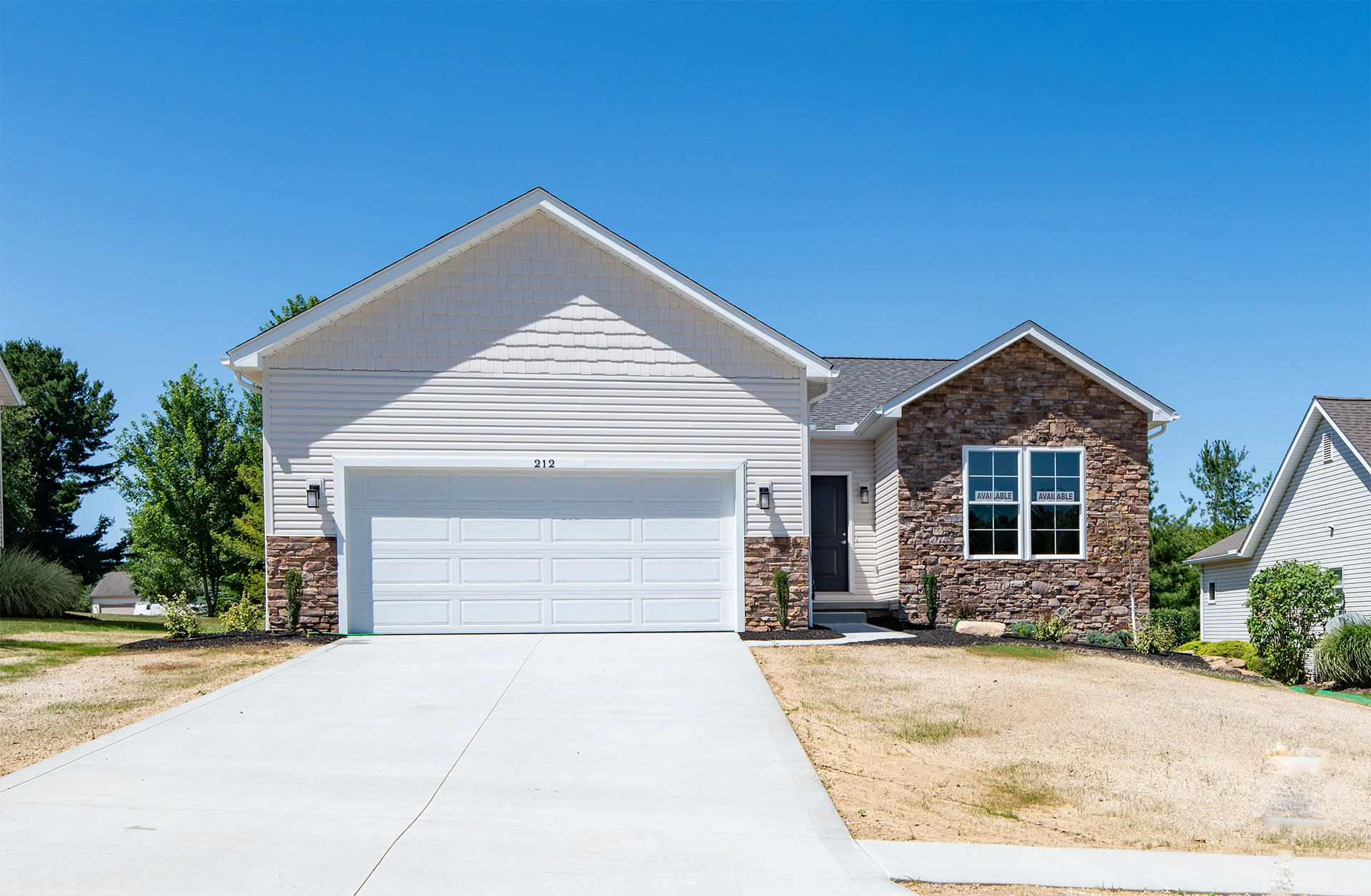 Front shot of a homes with a garage driveway and brick accents