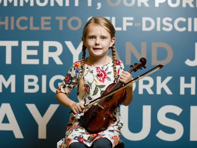 Young violin student smiling with her violin at Powell Academy of Music in Powell, Ohio