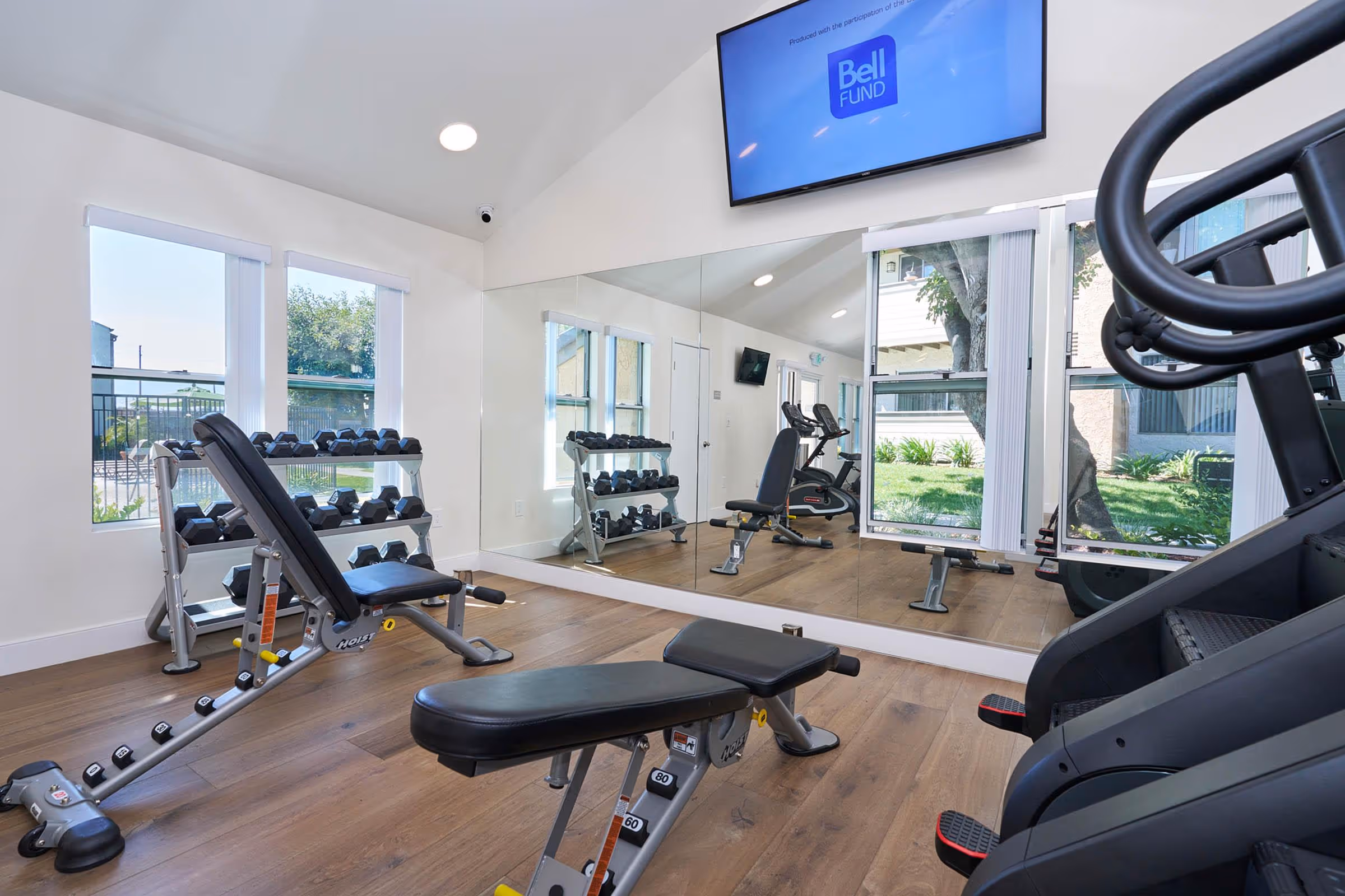 Gym with dumbbells, weight bench, and stair masters