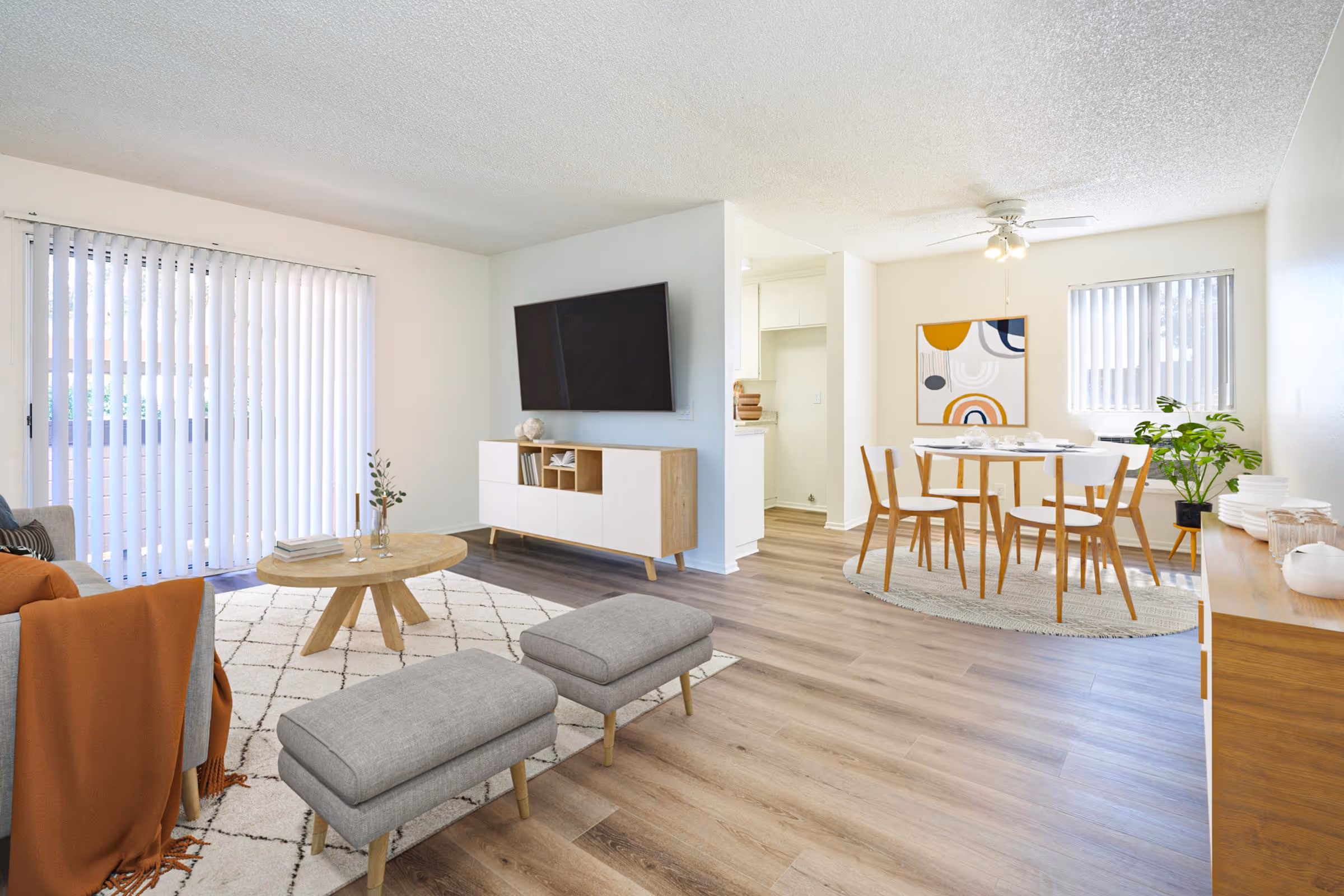 Wide view of Virtually staged living area featuring sofa, coffee table, and large window and dining area with table and chairs