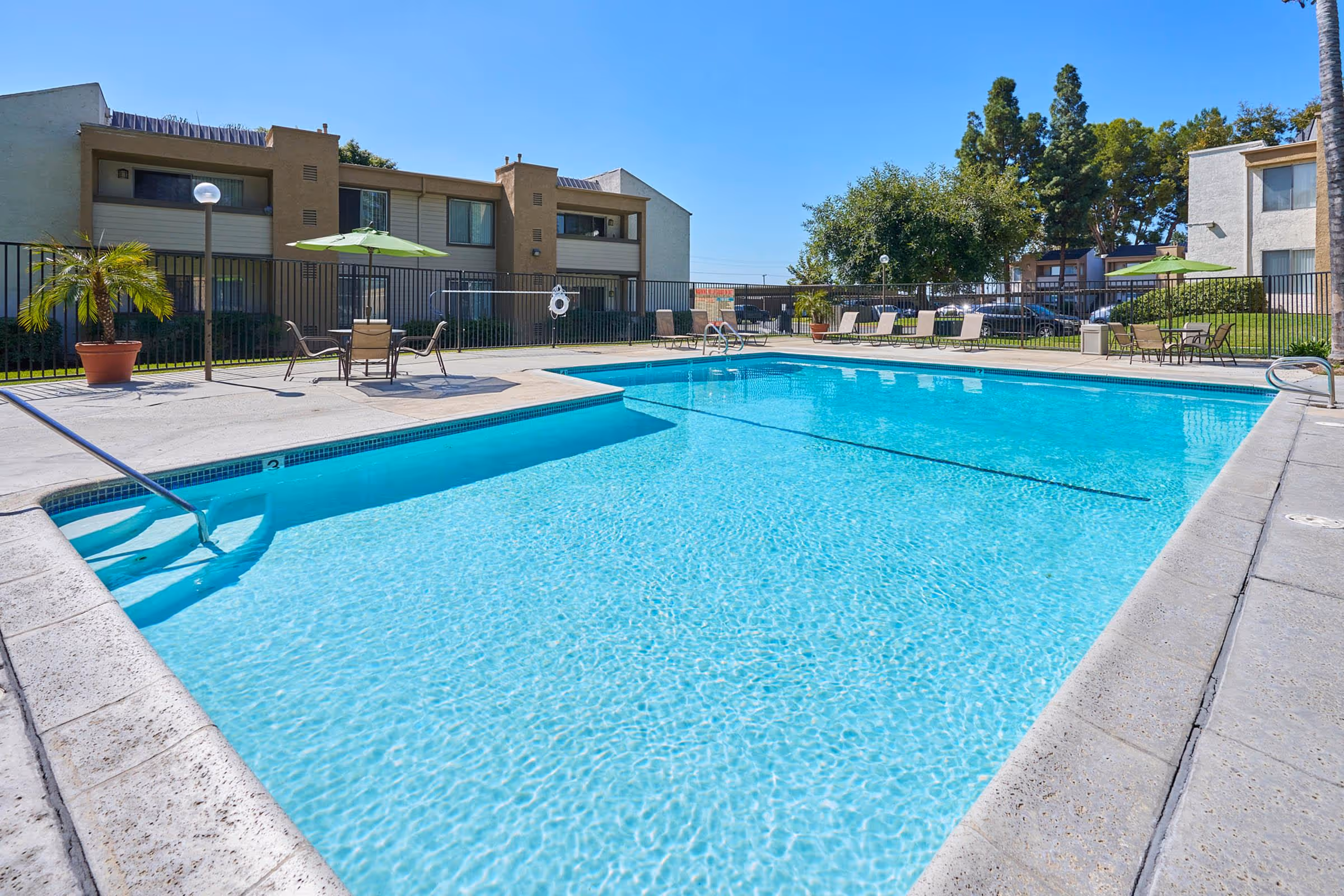 Swimming pool with lounge chairs and tables with chairs and umbrellas