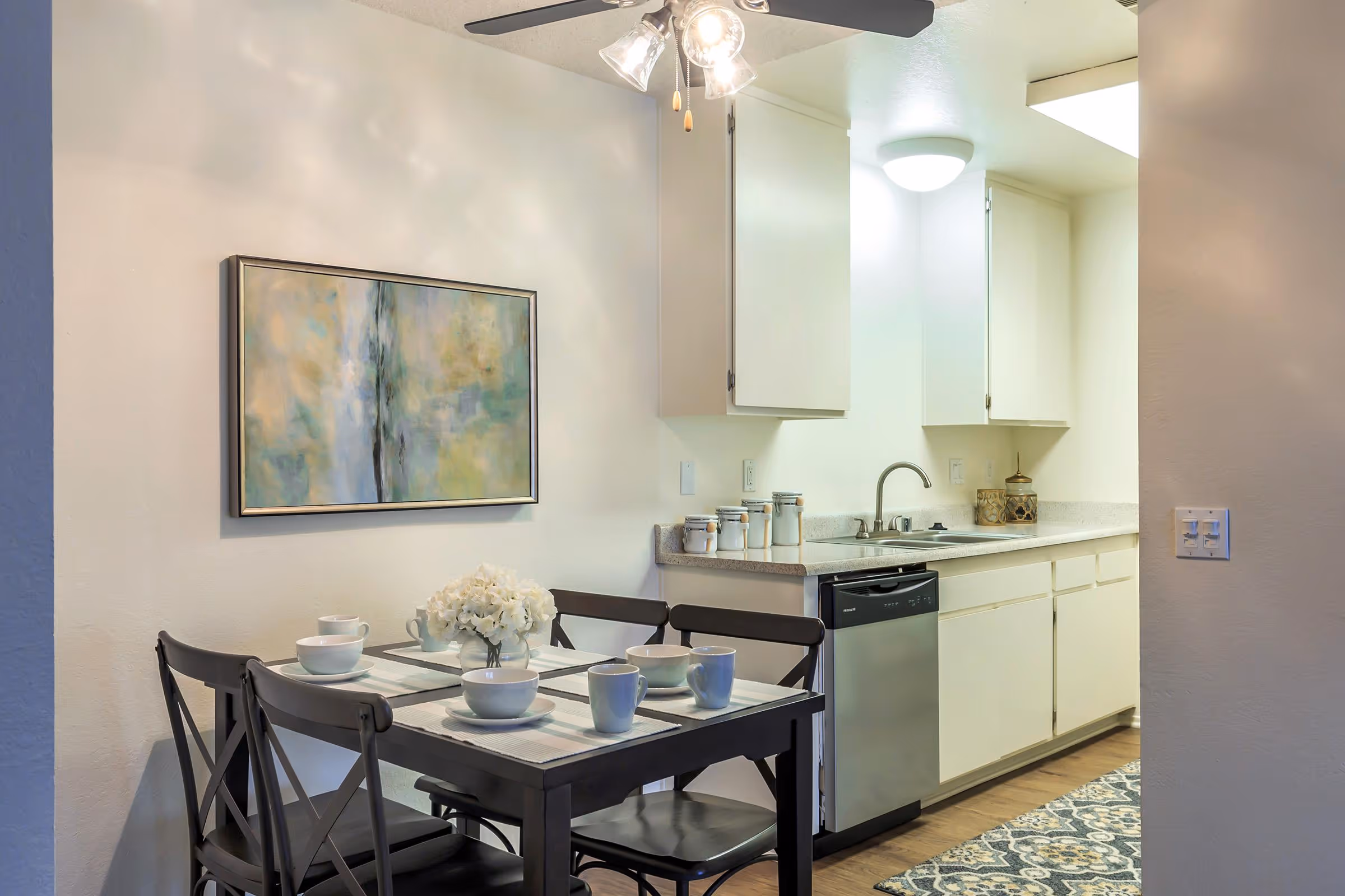 Dining area with table with chairs and view into kitchen with white cabinets 