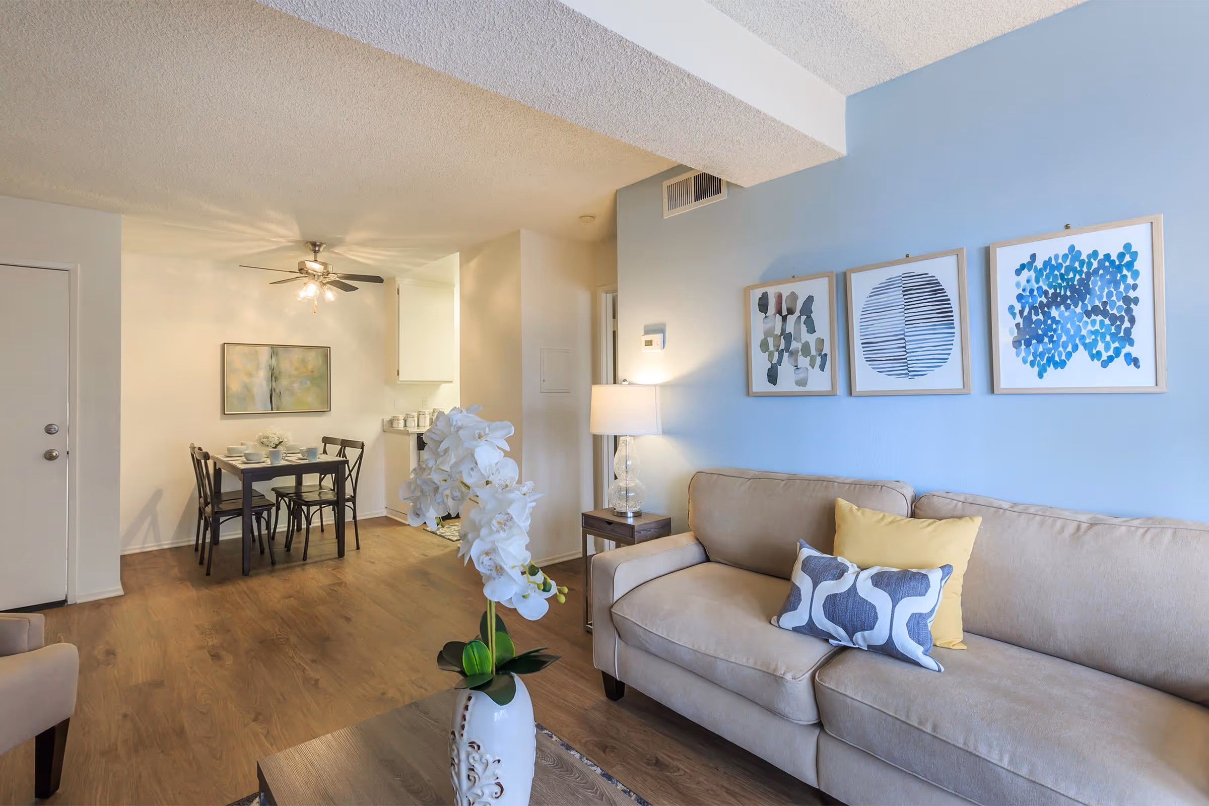 Wide view of living area featuring sofa, coffee table, and wall art and dining area with table and chairs