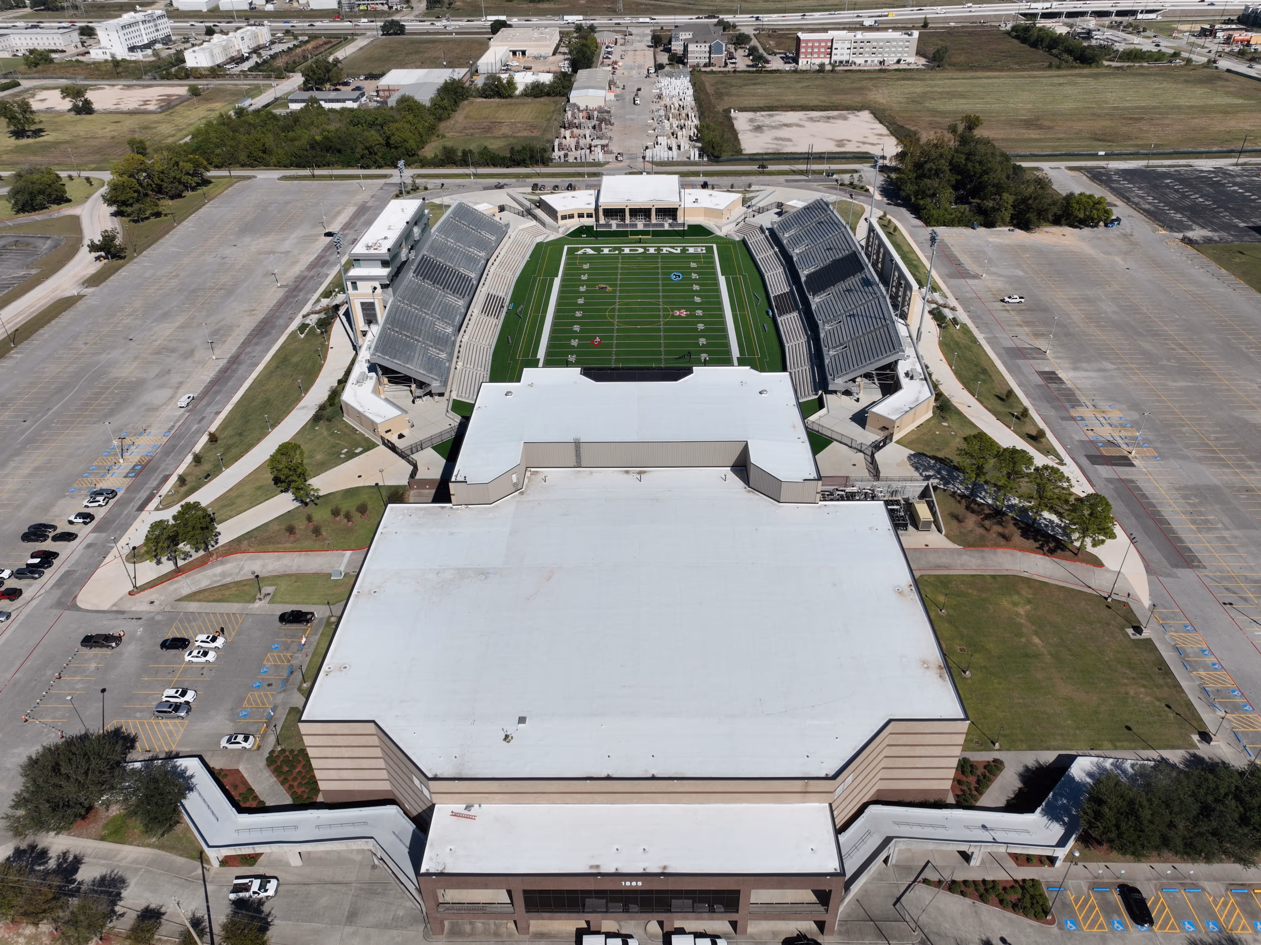 Aerial view of Aldine football stadium with empty stands and surrounding parking lots.