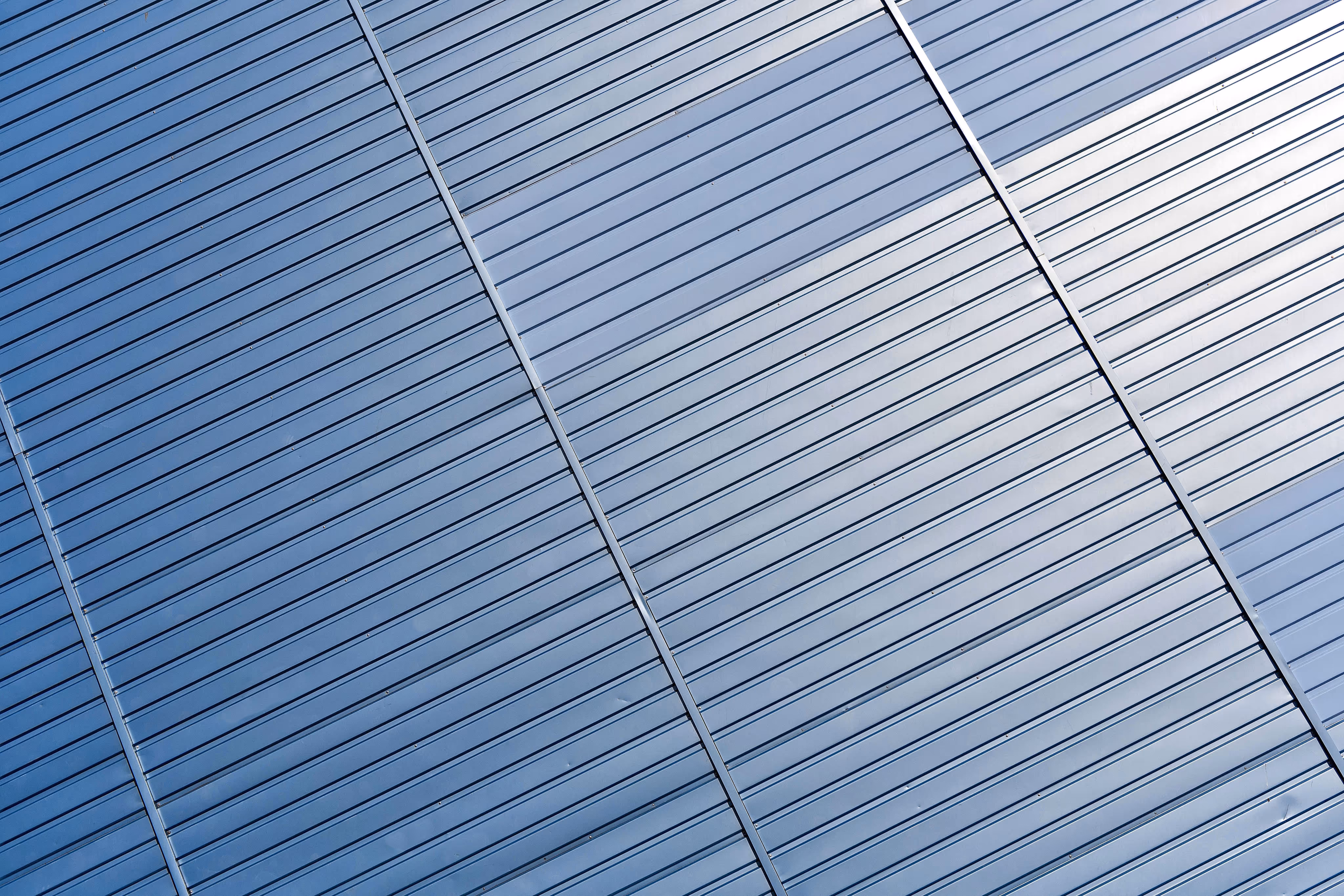 Close-up of corrugated metal panels with reflective blue-gray surface and diagonal alignment.