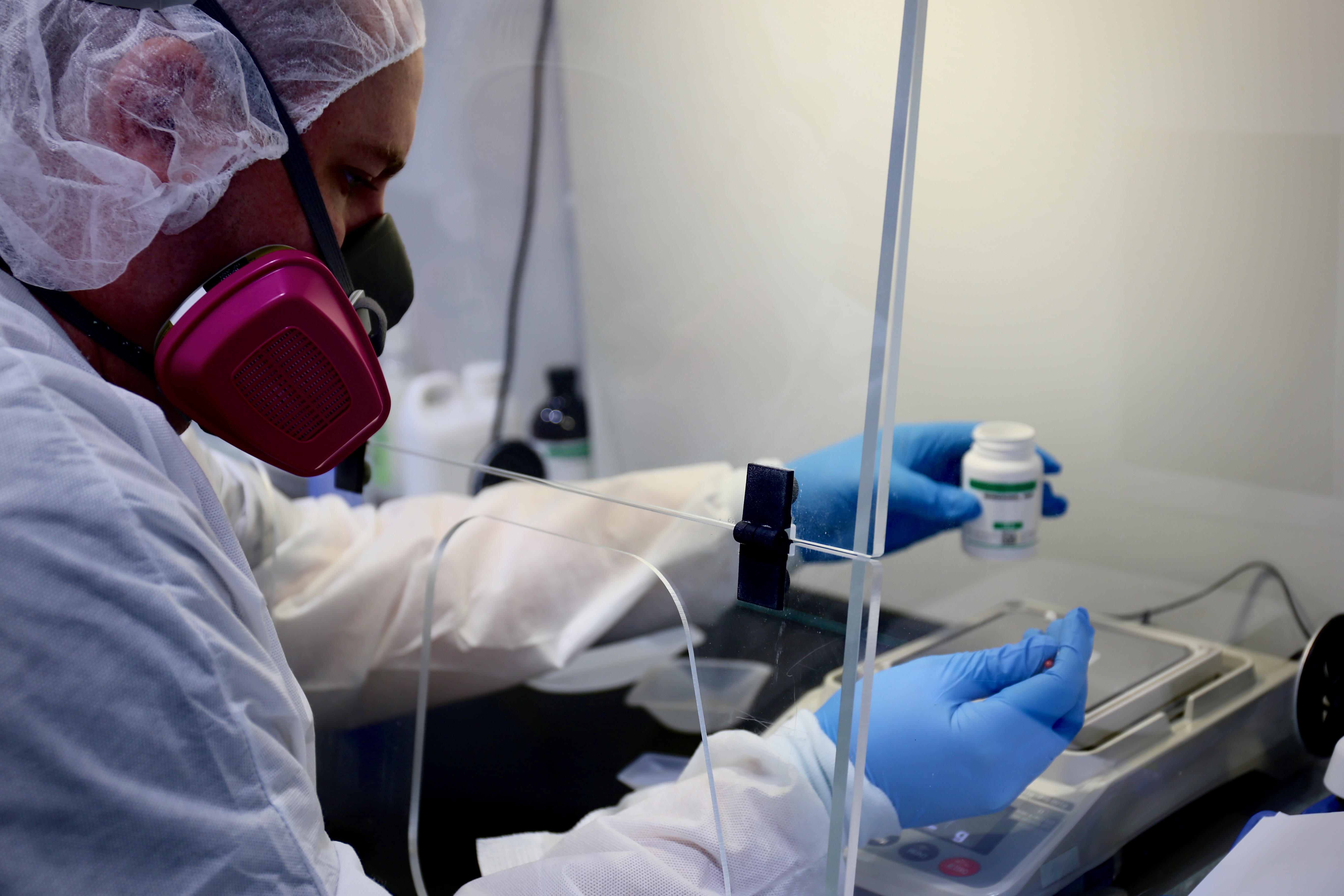 Southcity Community Pharmacy compounder in full protective gear preparing a custom medication in the laboratory