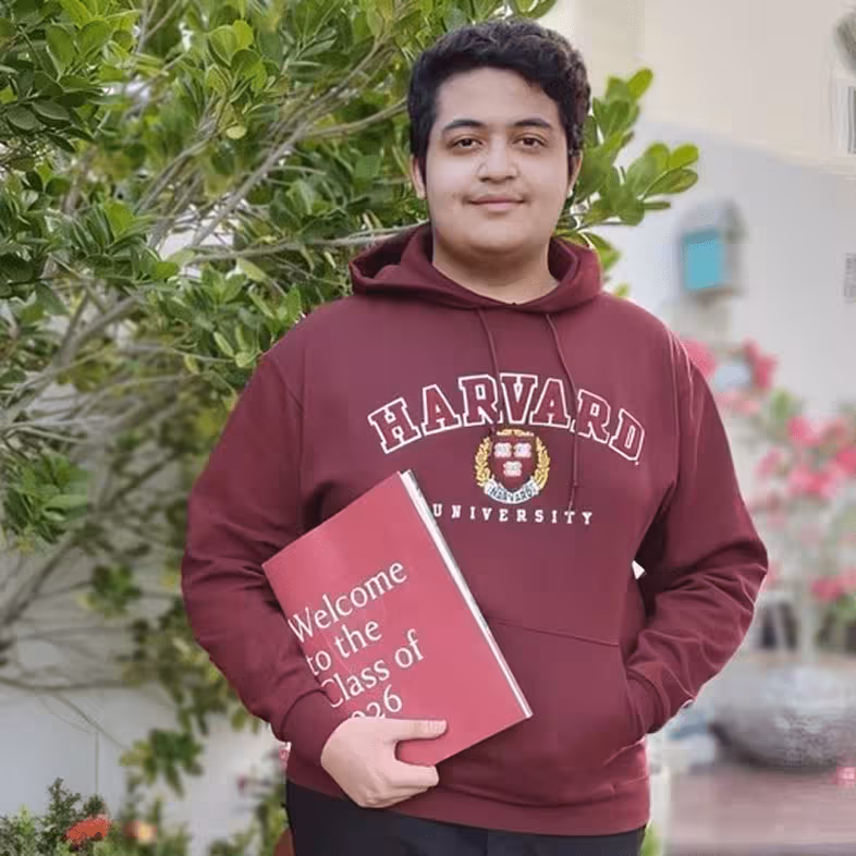 Teen wearing Harvard University hoodie holding a sign that says Welcome to the Class of 2026.