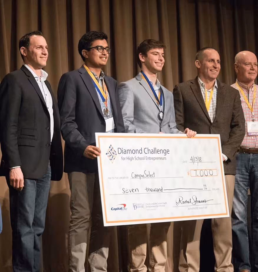 Five men on stage holding a $7,000 Diamond Challenge check for high school entrepreneurs.
