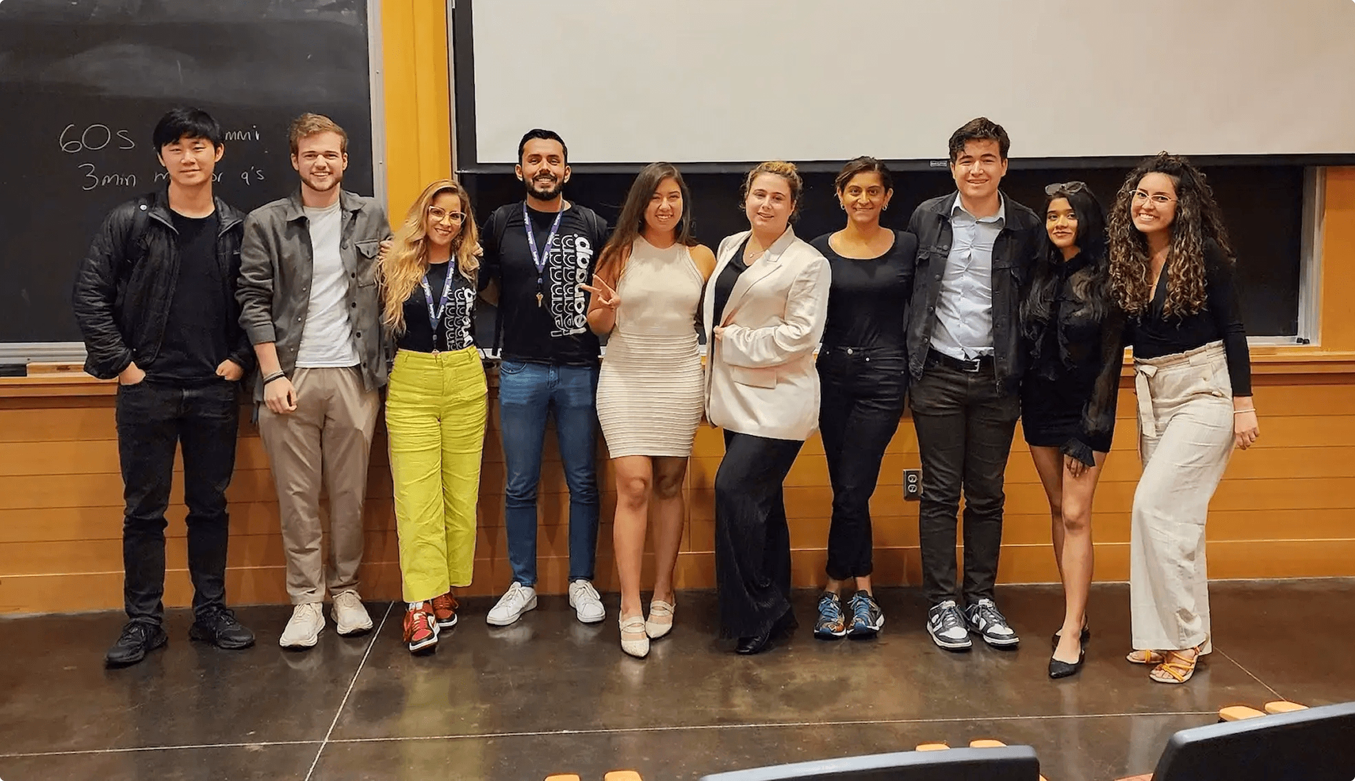 Group of ten mentors standing in a classroom in front of a chalkboard and projector screen.