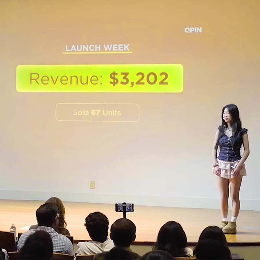 Young founder on stage beside a slide showing $3,202 revenue and 67 units sold