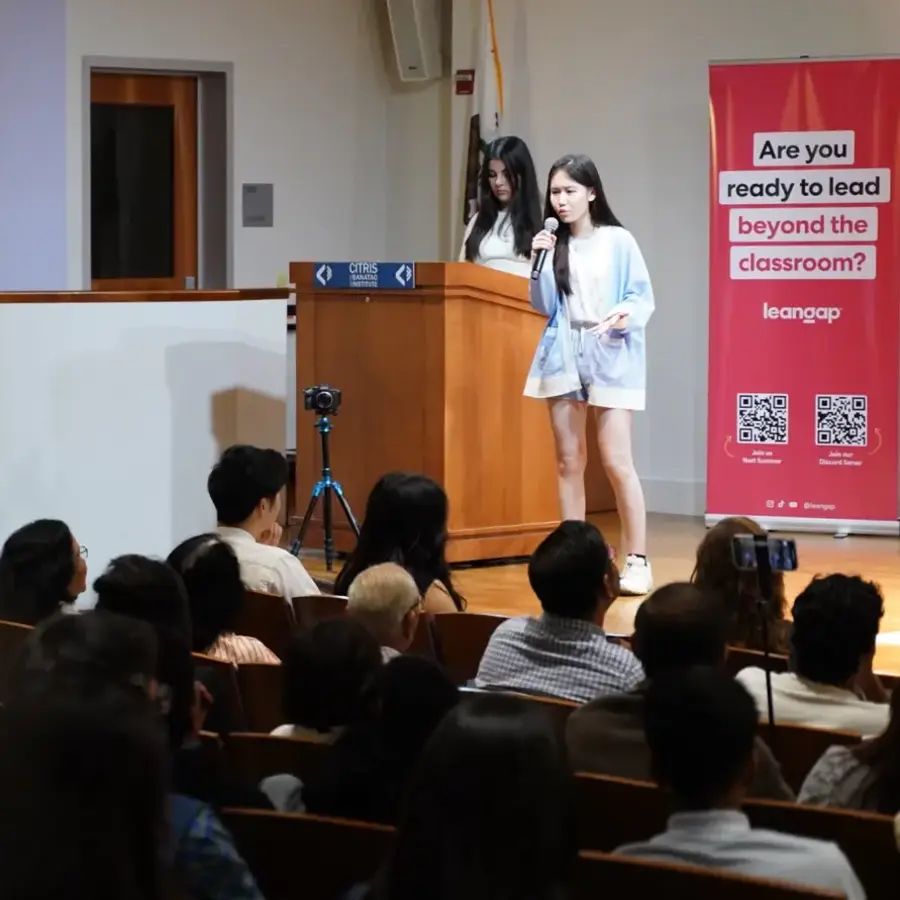 Young founder pitching into a microphone to a seated audience at Leangap Demo Day