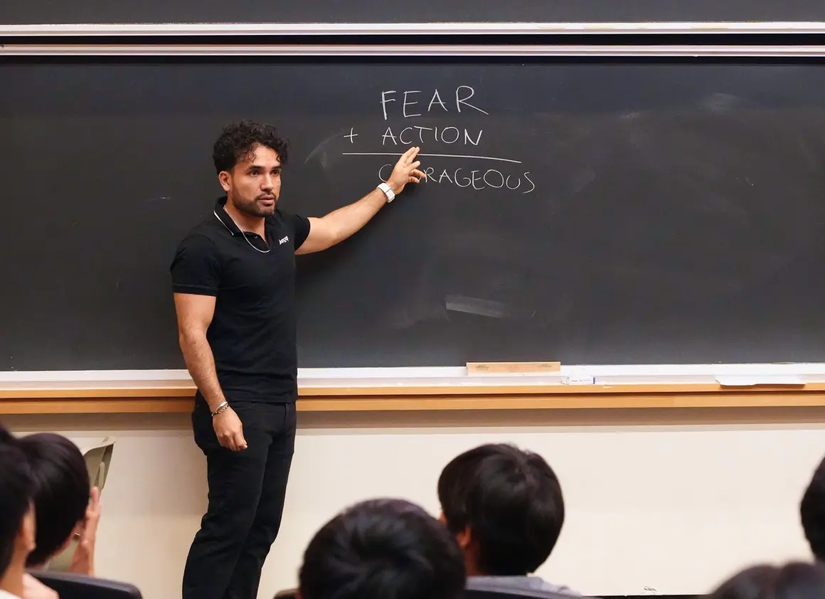 Mentor pointing to a chalkboard reading "Fear + Action = Courageous" while teaching Leangap students