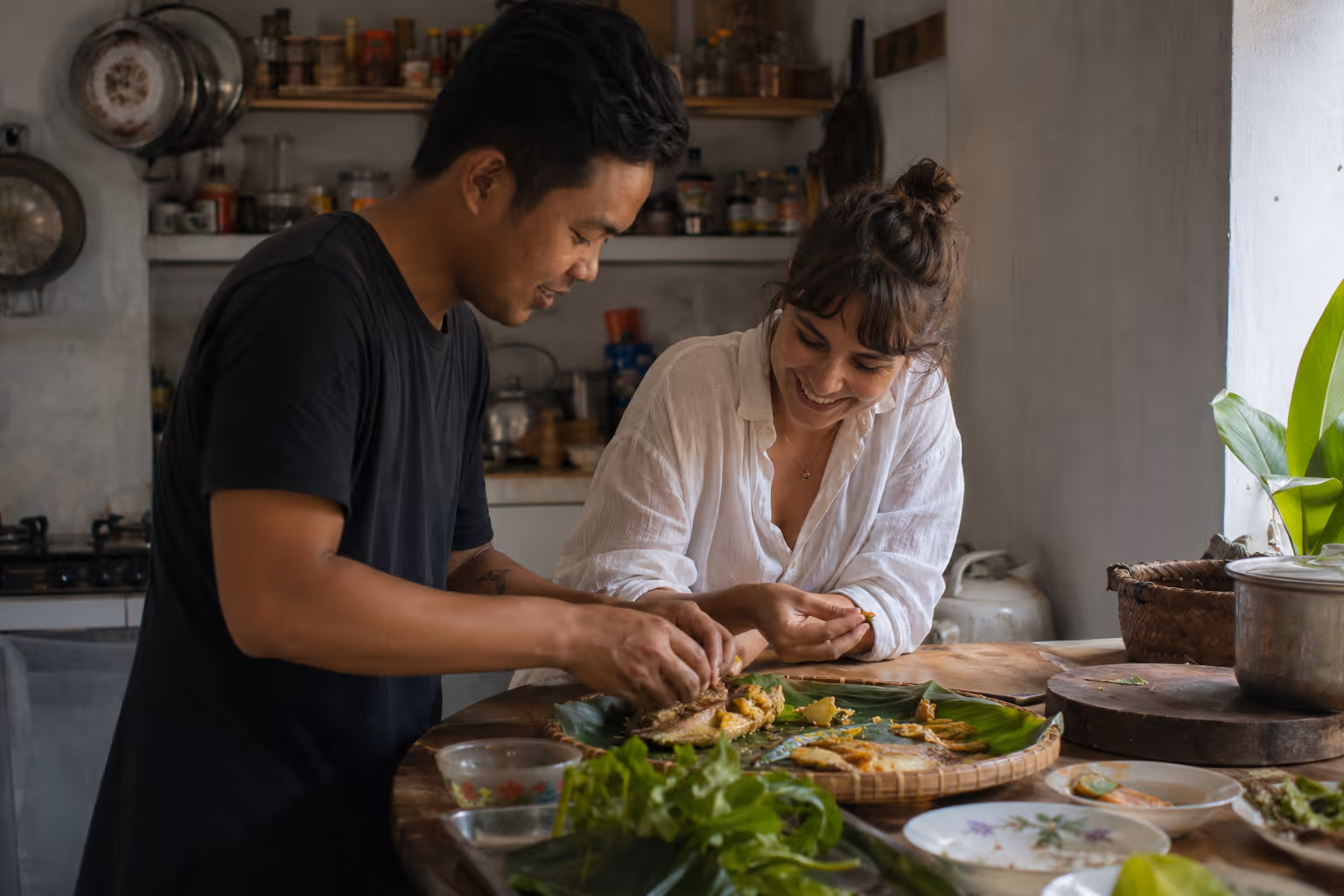 A local and traveler cooking together in a kitchen, sharing a meal