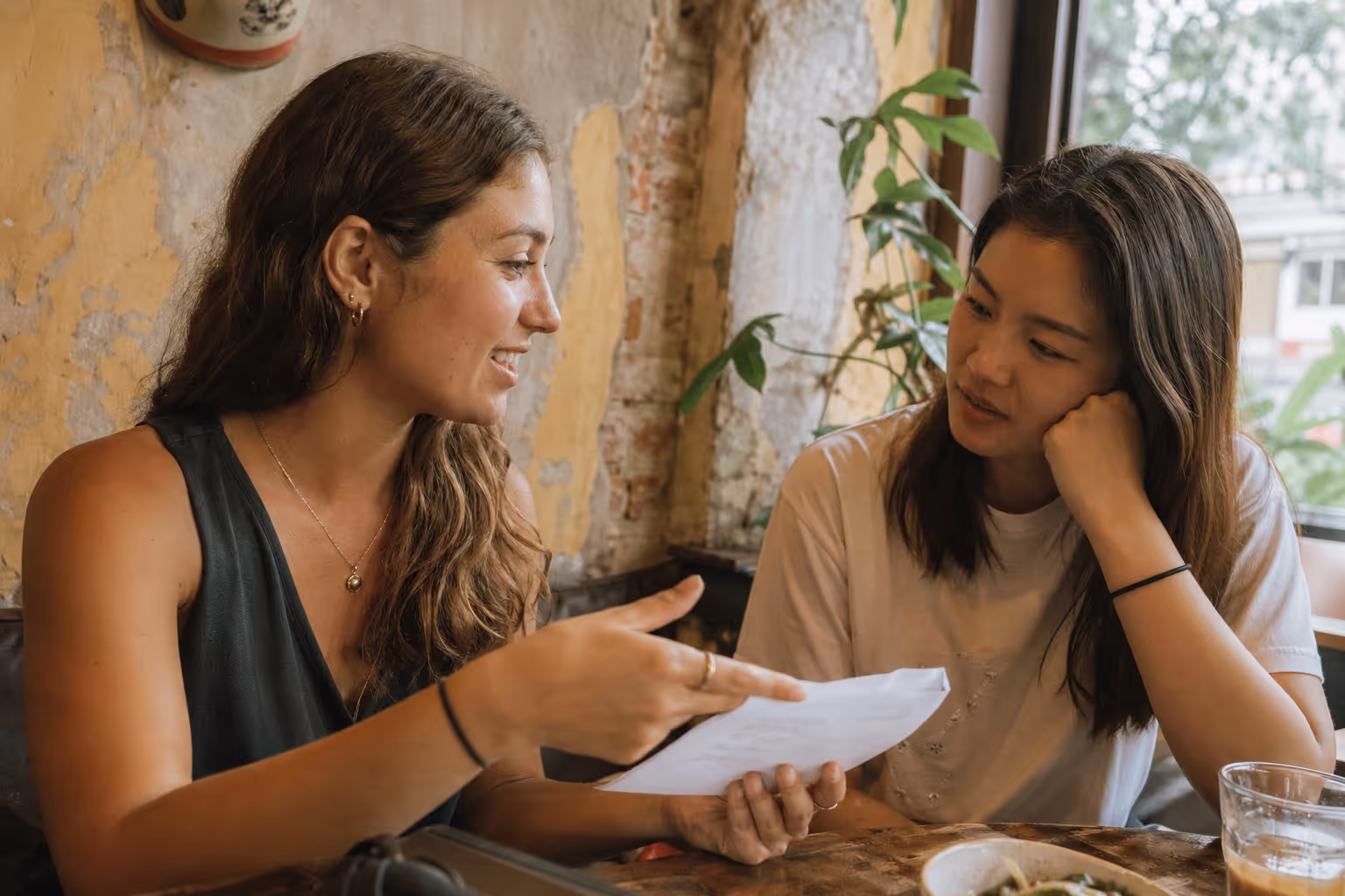 Two women at a café sharing notes and ideas during a cultural exchange