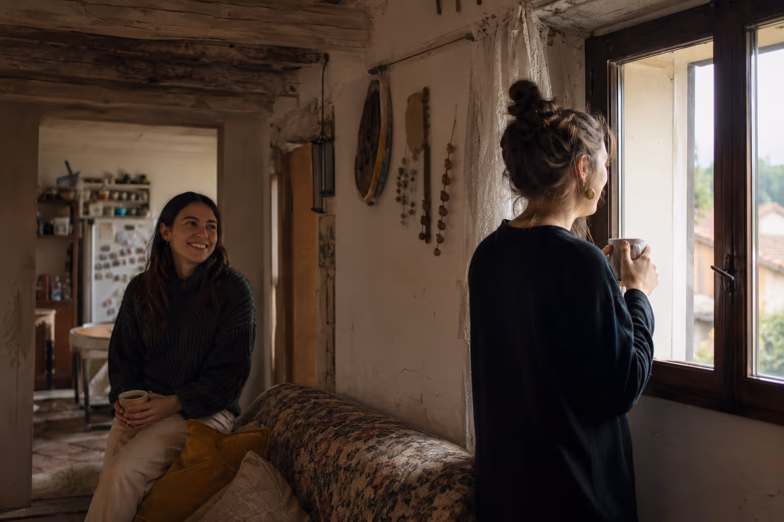 Two women sharing a warm conversation over tea in a cozy rustic home