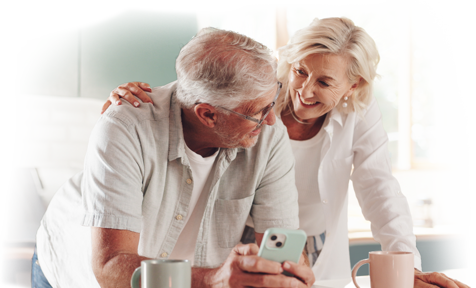 Couple wearing white and white hair looking at phone with their Free Newsletter and smiling