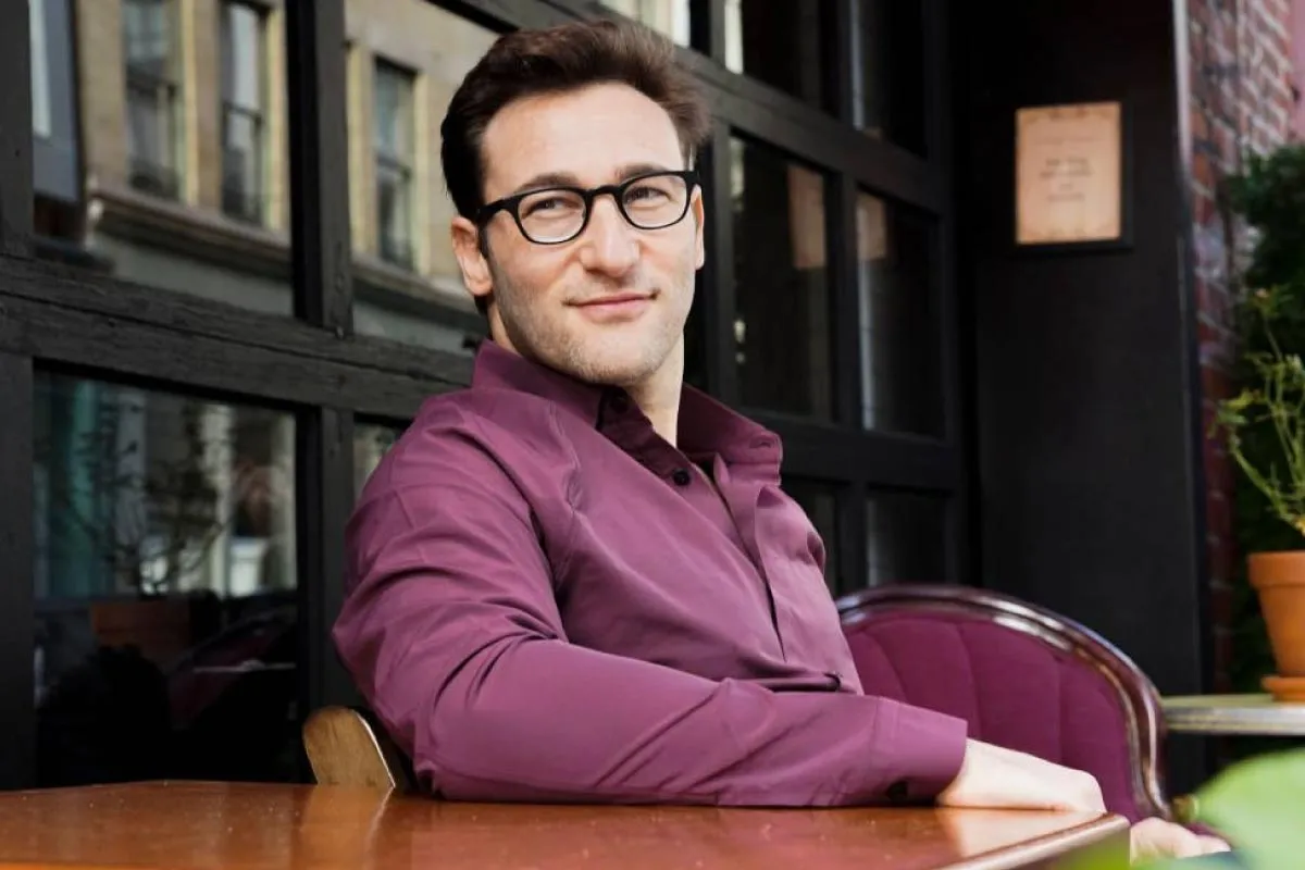 Simon Sinek smiling confident outside of a cafe.
