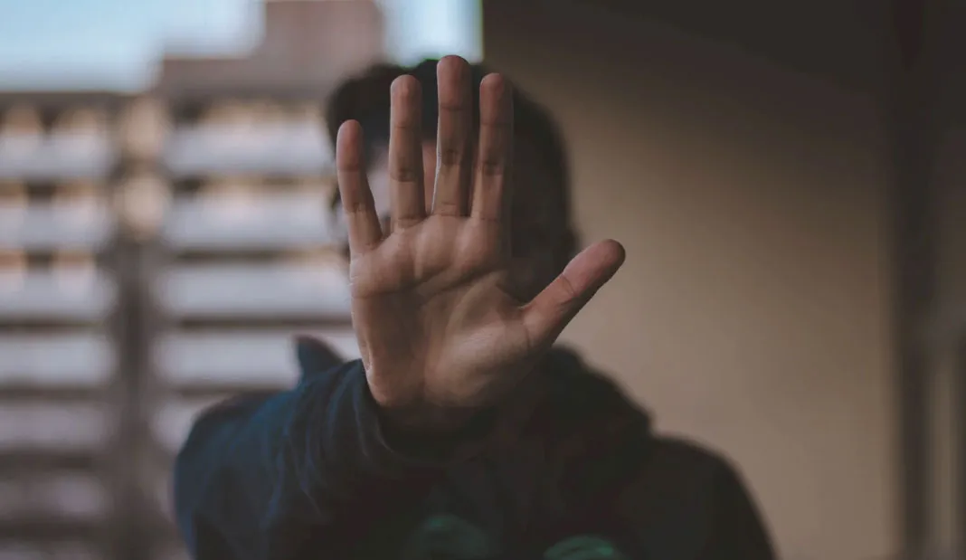 A man standing with his open palm in front of him in a sign of “stop.”
