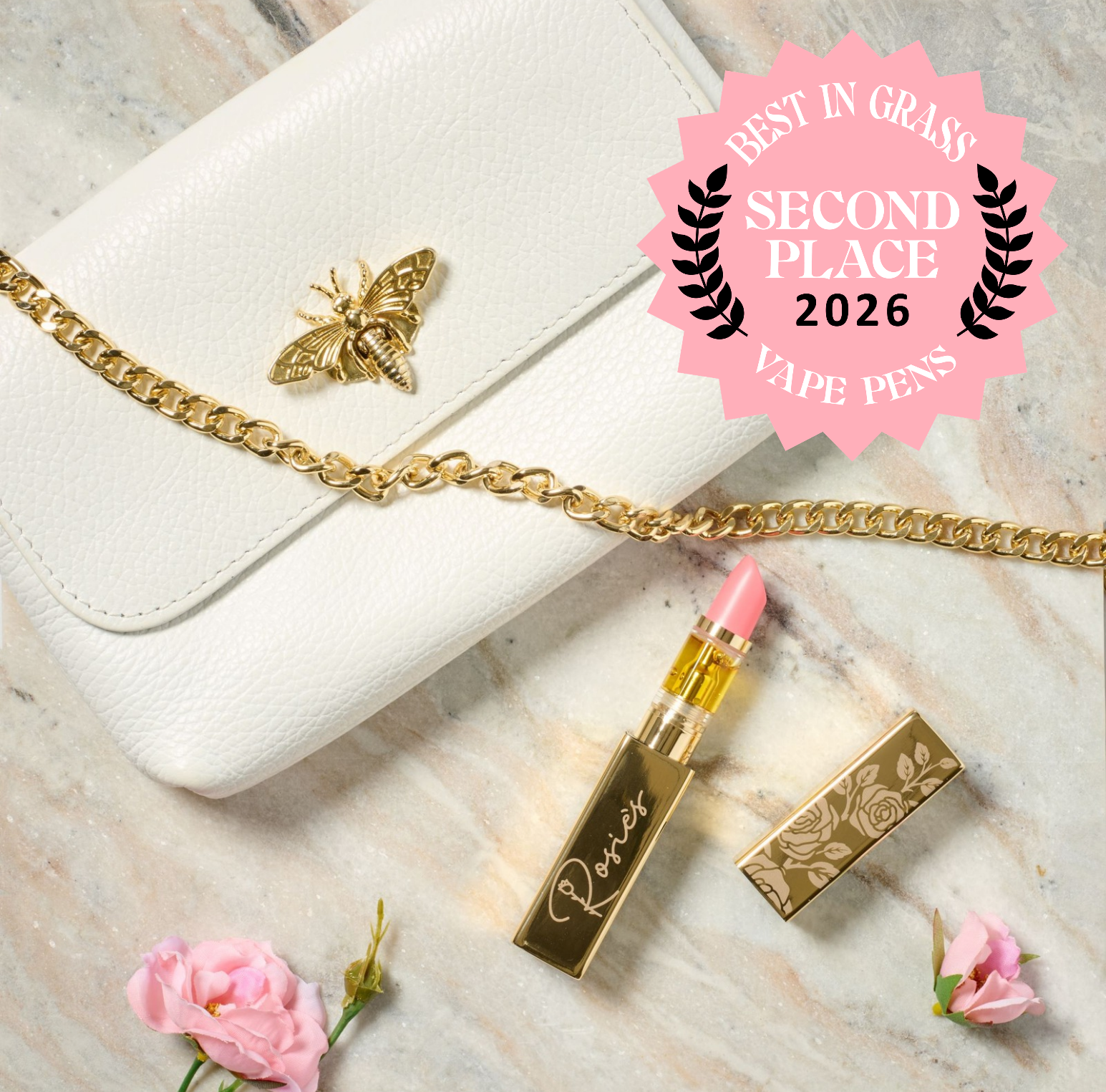 White leather purse with gold bee emblem and chain next to gold lipstick with pink tip and pink flowers on marble surface.