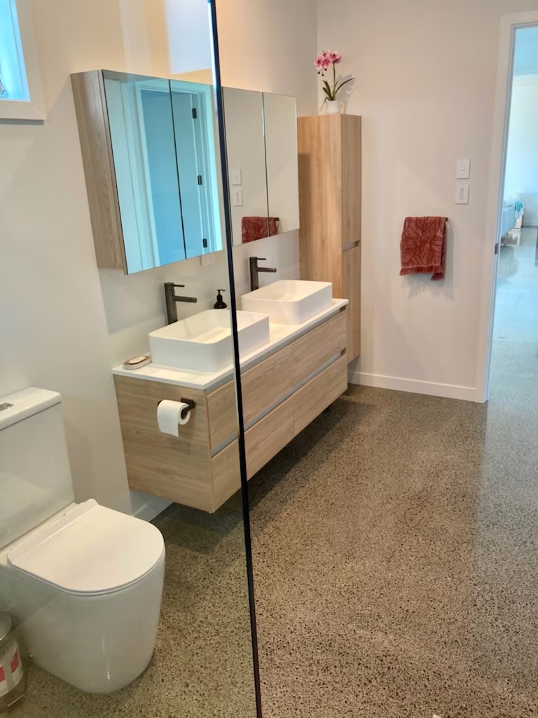 Modern bathroom renovation with double vanity and polished concrete floor by Bay Construction