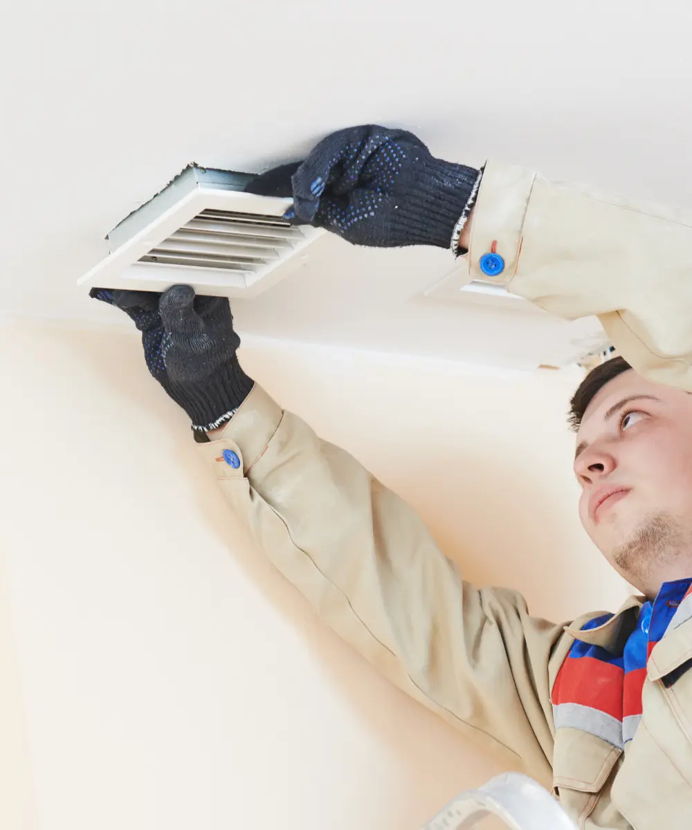 Technicien installant une grille de ventilation au plafond
