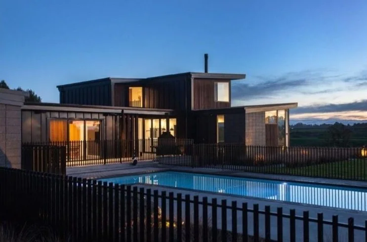 Illuminated pool and modern home at dusk, pool landscaping Waikato