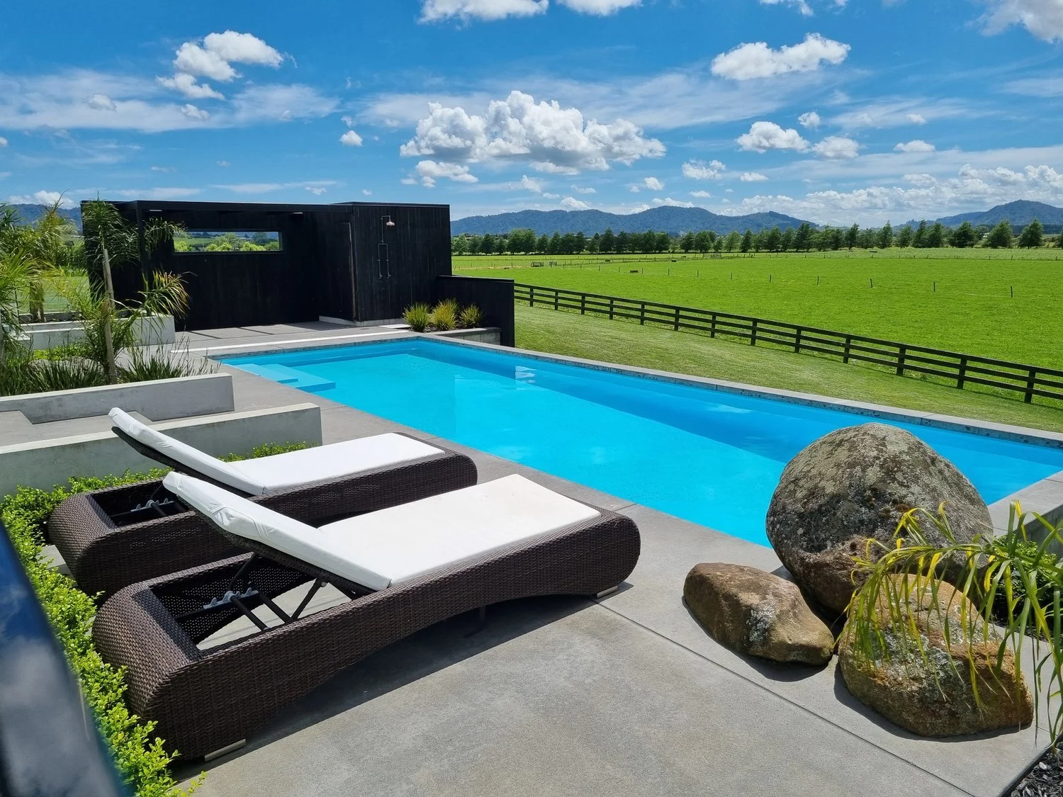Resort-style pool with sun loungers and boulder features, Waikato