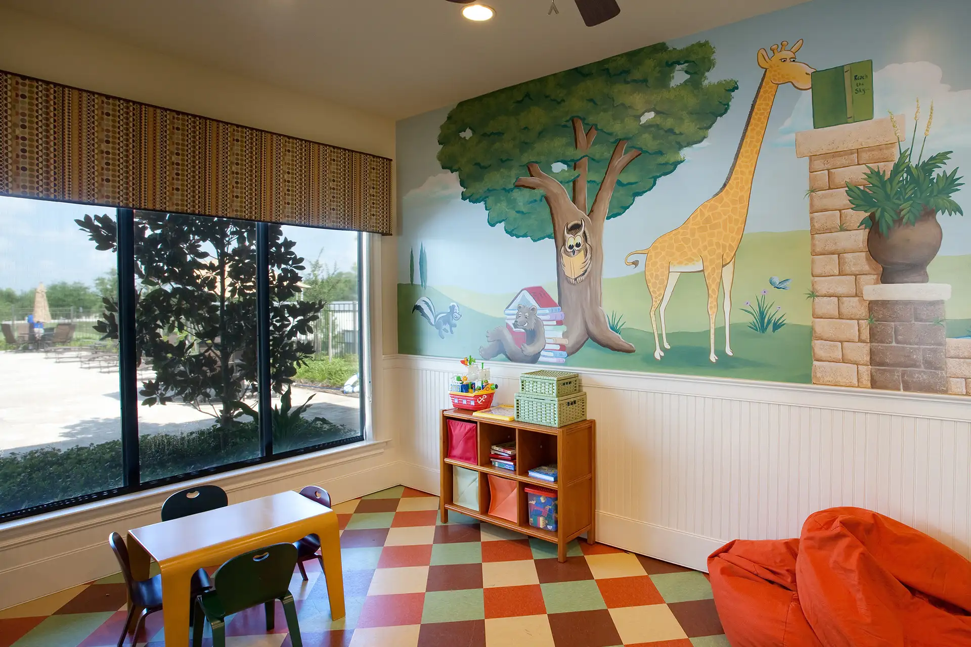 Children's play area with jungle-themed mural at The Quarters Apartment Homes