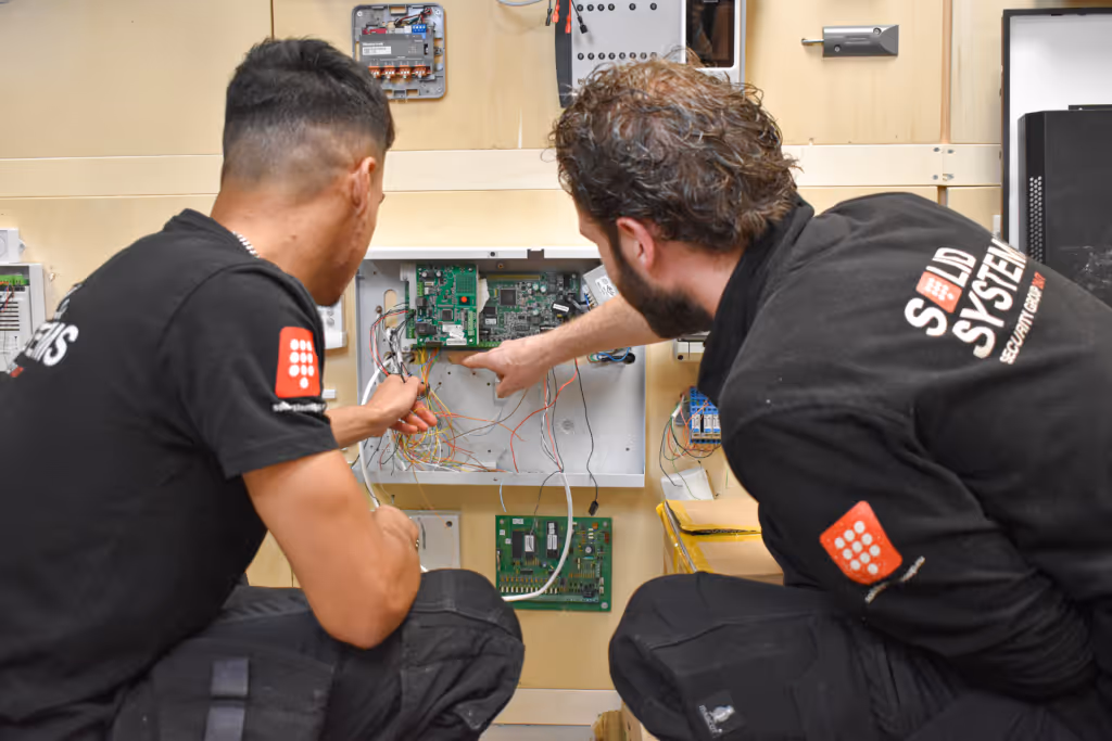 Ervaren installatiemonteur geeft uitleg aan nieuwe monteur van Solid Systems.