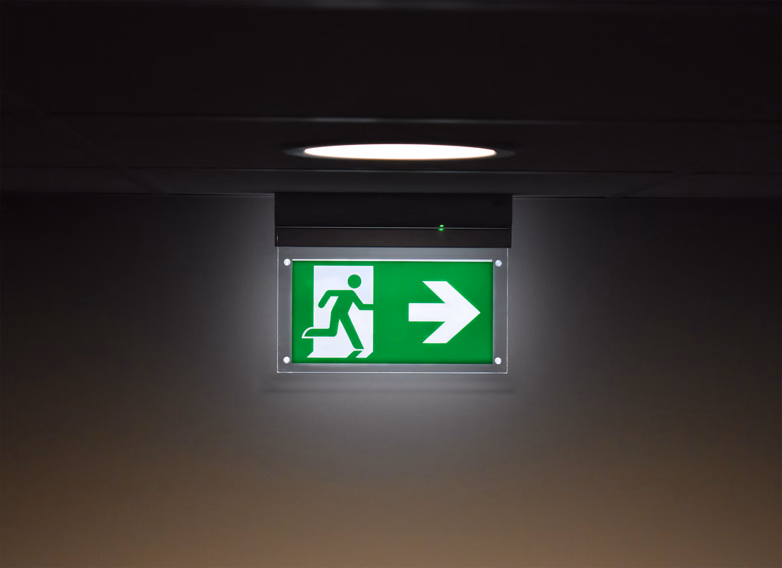 Goed zichtbare noodverlichting van Solid Systems verwijzend naar de nooduitgang bevestigd tegen het plafond. 