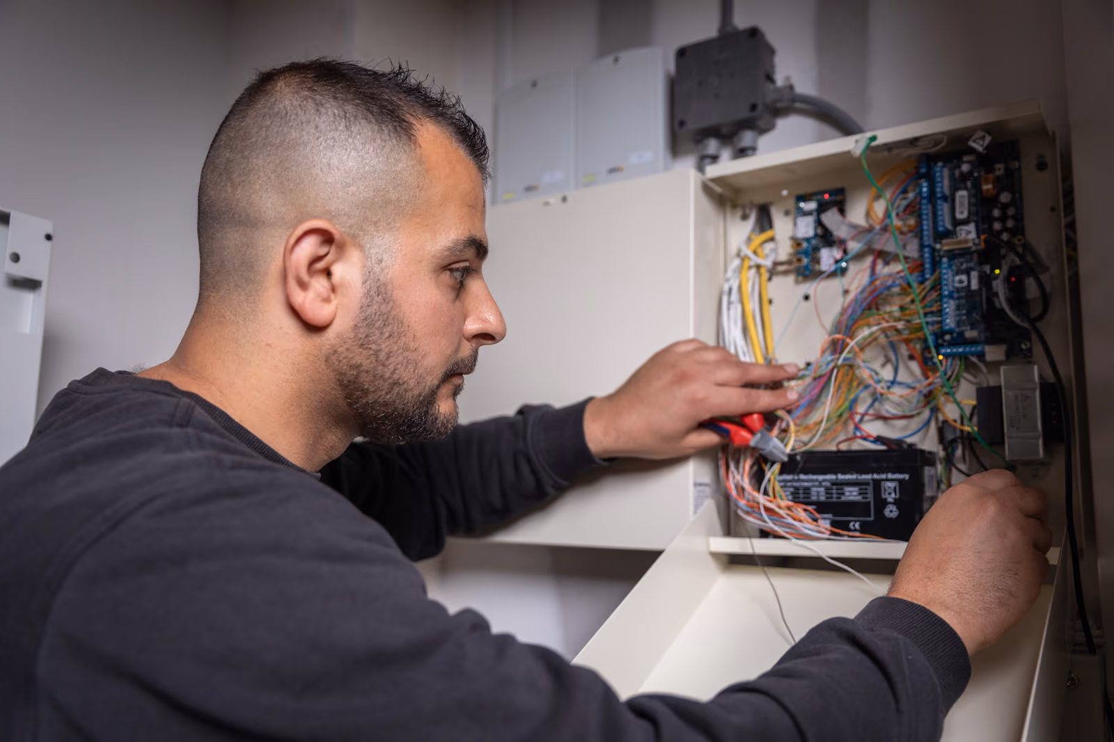 Een elektromonteur van Solid Systems bevestigd de juiste bedrading in een schakelkast. 