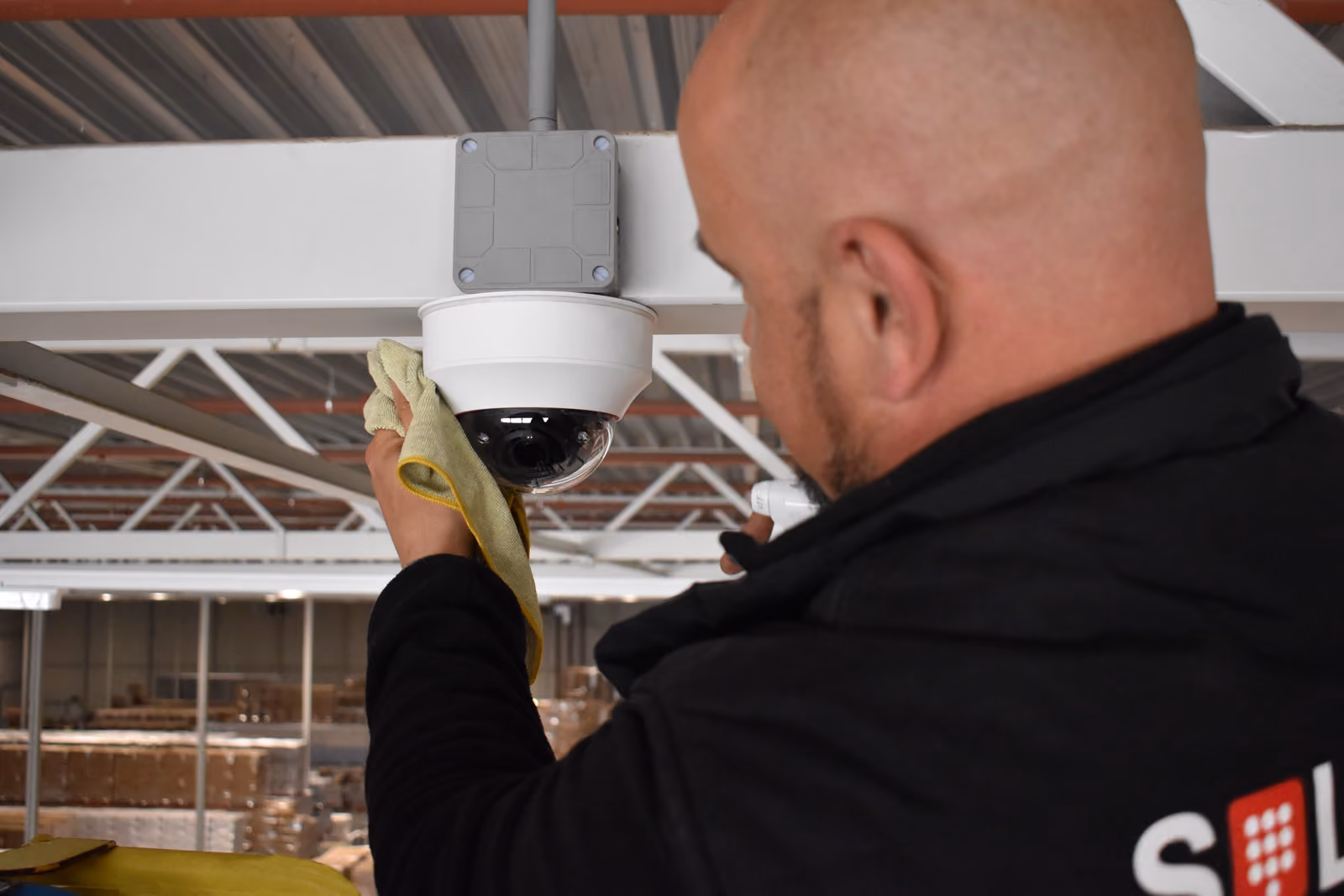 Een servicemonteur van Solid Systems poets de nieuwe beveiligingscamera naar plaatsing. 