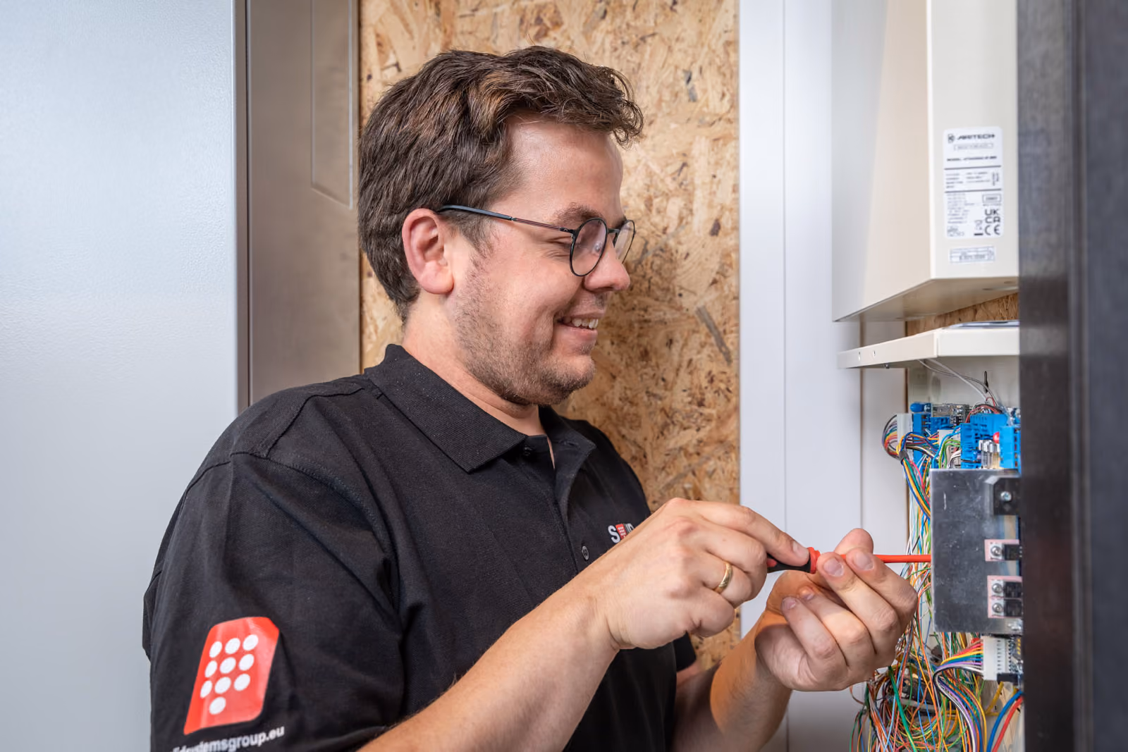 Een enthousiaste monteur van Solid Systems werkt met een schroevendraaier en rond zijn werkzaamheden af.  