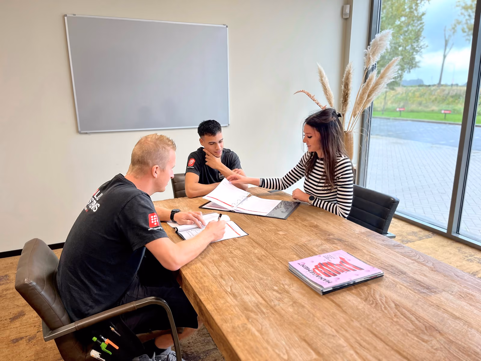 Een medewerker van HR loopt samen met een nieuwe monteur door zijn nieuwe arbeidsovereenkomst.