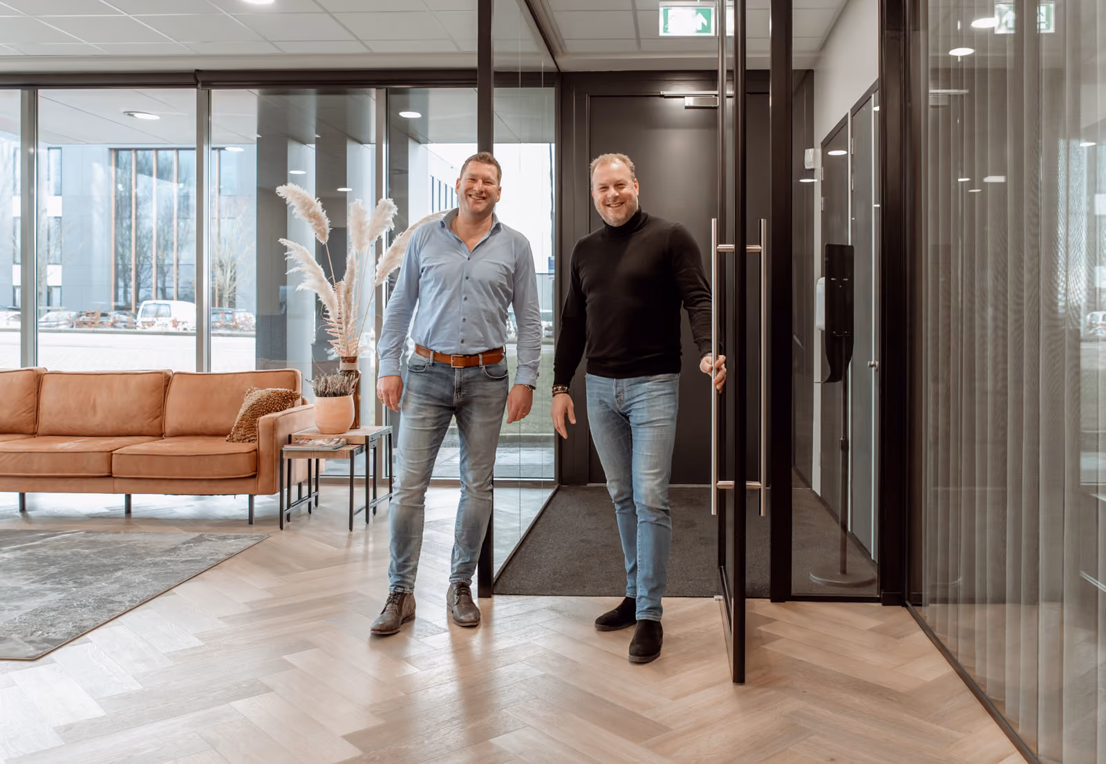 Twee trotse medewerkers heten je van harte welkom bij de ingang van het kantoor van Solid Systems.