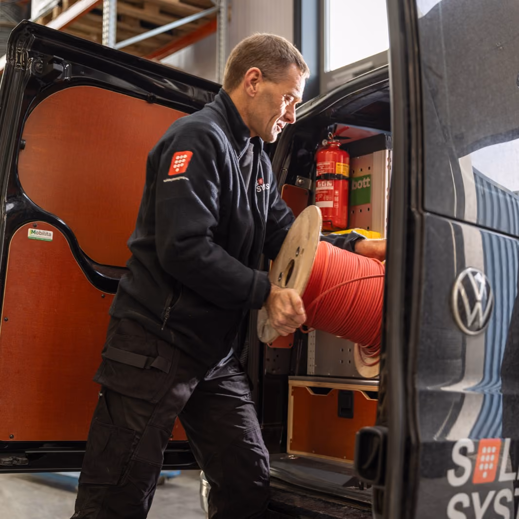 Een servicemonteur van Solid Systems is zijn bus aan het laden met kabels. 