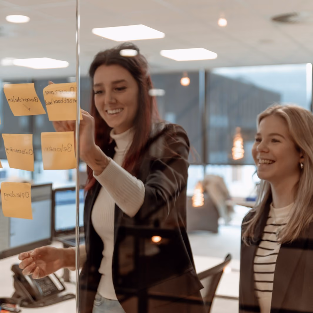 Twee vrouwen lachend tijdens een brainstormsessie bij Solid Systems.