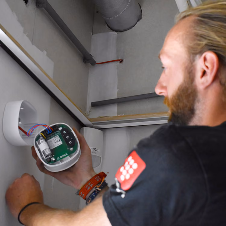 Solid Systems monteur bevestigd alarminstallatie. 