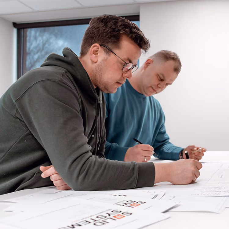 Twee werkvoorbereiders bij Solid Systems die een werktekening uitwerken voor een klant.