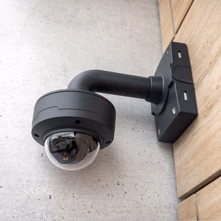 Een onopvallende zwarte camera gemonteerd tegen een houten wand.